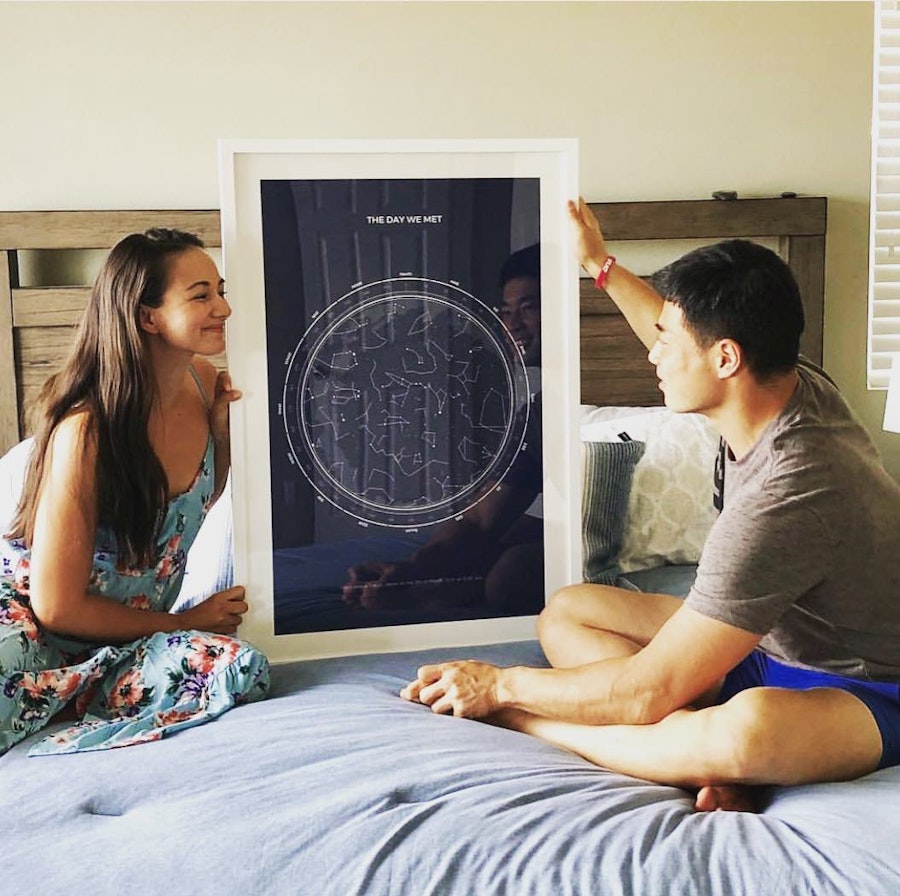 Smiling couple next to their black star map with white frame